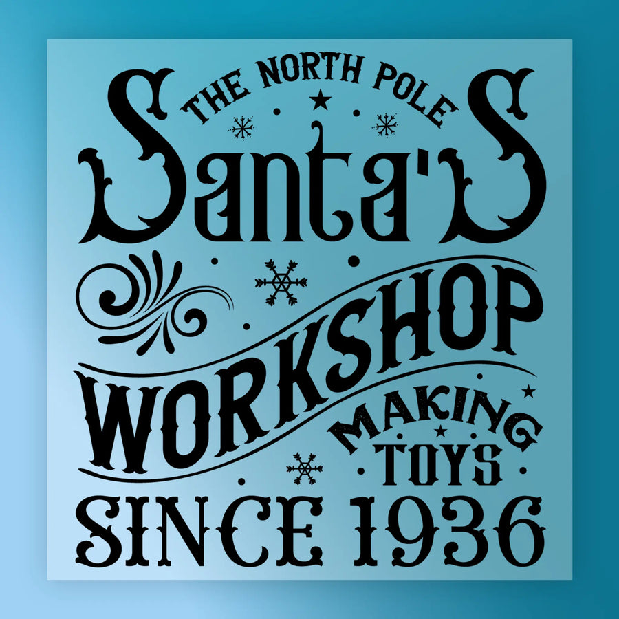 The North Pole Santa's Workshop Design by InkMerge is a decorative DTF transfer with ornate fonts, snowflakes, and swirls on blue—precut and ready to press for easy holiday crafting.
