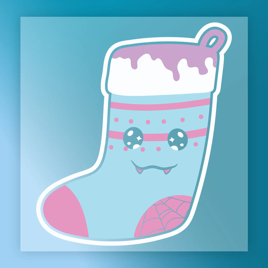 The InkMerge Quirky Vampire Christmas Stocking transfer showcases a pastel blue, pink, and white cartoon stocking with fangs, starry eyes, and a spiderweb—ideal for DTF transfers or your next ugly sweater party!.