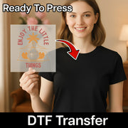 A smiling woman in a black t-shirt holds an InkMerge DTF sheet that reads Get Your Fat Pants Ready Thanksgiving Humor with an arrow to her shirt. Text above says Ready To Press—perfect for custom apparel or Thanksgiving transfers.