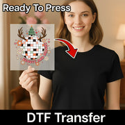 A smiling woman in a black shirt holds the InkMerge Groovy And Bright Disco Christmas Design DTF transfer, featuring a disco ball, antlers, flowers, and text. Caption: Ready To Press—perfect for your holiday heat press projects.