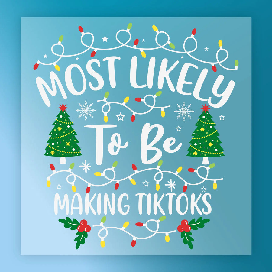 InkMerge "Most Likely To Be Making TikToks" DTF transfer features festive white and yellow text with Christmas lights, trees, and snowflakes on a blue background—perfect for your holiday projects. Ready to press!.