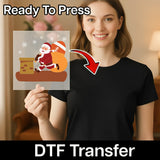 A smiling woman in a black shirt holds the "Cheerful Santa Claus Chimney Scene" by InkMerge. "Ready To Press" appears above and "DTF Transfer" below, with an arrow showing the design transferring to her festive shirt.