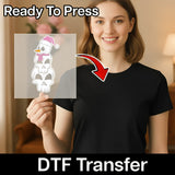 A woman in a black shirt holds an InkMerge Quirky Snowman Pink Santa Hat Design DTF transfer sheet, featuring stacked cartoon snowmen with “Ready To Press” and “DTF Transfer”—perfect for your next heat press project.