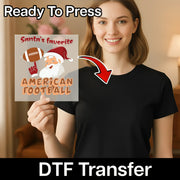 A smiling woman in a black shirt holds the InkMerge "Santa's Favorite American Football" DTF transfer sheet, showing a cartoon Santa with a football and "Ready To Press" displayed above. Ideal for game day!.