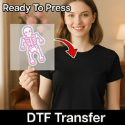 A smiling woman in a black shirt holds a clear sheet with InkMerge’s Cute Pastel Skeleton Kawaii Design. An arrow points to her shirt. Text above reads "Ready To Press" and below, "DTF Transfer"—ideal for Halloween crafts.
