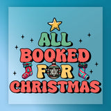 The "All Booked For Christmas Funny Design" by InkMerge features bold, colorful text with stockings, a star, ornament, and small stars on a blue background—perfect for a festive holiday shirt transfer.