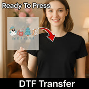 A smiling woman in a black t-shirt holds an InkMerge DTF transfer sheet featuring the Sweater Weather Festive Design, highlighting its Ready To Press feature and compatibility with heat press machines.