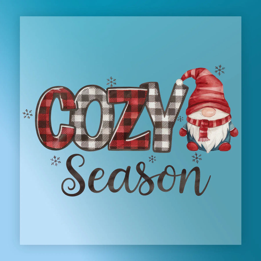 Season Gnome Plaid by InkMerge features "cozy season" in plaid letters with a red-hatted gnome beside it, set on a snowy blue background—ideal for festive apparel using DTF transfer or heat press on premium DTF film.