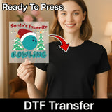 A smiling woman in a black shirt holds an InkMerge "Santa's Favorite Bowling Christmas Design" DTF transfer sheet featuring a Santa hat on a bowling ball, two Christmas trees, and an arrow pointing to her shirt. Text above says Ready To Press.
