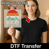 A woman in a black t-shirt holds a clear transfer sheet with the Mountain Adventure Retro Design by InkMerge. "Ready To Press" appears at the top, "DTF Transfer" at the bottom—perfect for your next mountain adventure project.