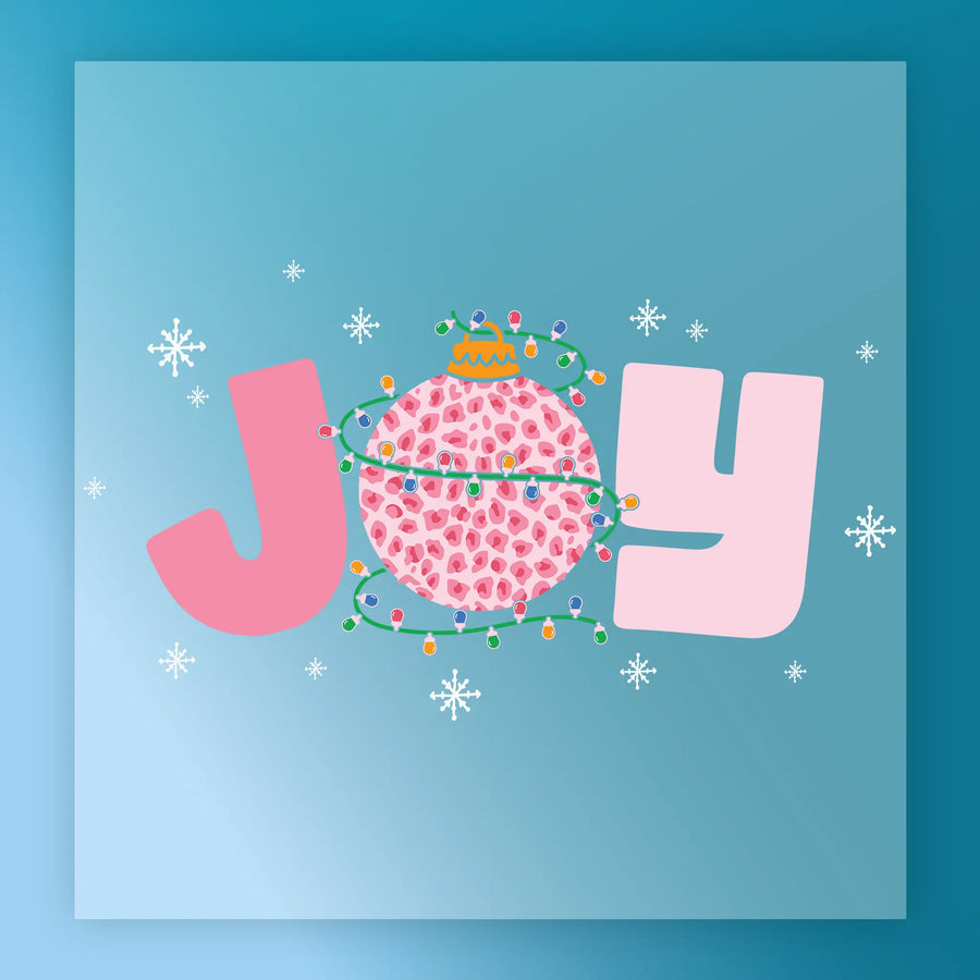 The Joy Leopard Ornament Christmas Lights DTF transfer by InkMerge features "JOY" in bold pink letters on blue, with the "O" as a festive ornament wrapped in Christmas lights and leopard print, surrounded by white snowflakes.