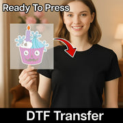 A woman in a black shirt holds a transparent sheet featuring InkMerge’s Halloween Winter Cupcake Design with a candle and blue frosting. The image displays "Ready To Press" at the top and "Halloween DTF transfer" at the bottom.