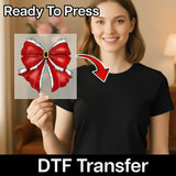 A woman in a black shirt holds InkMerge's Santa Bow Christmas Design DTF transfer sheet, featuring a red bow, white fur trim, and gold buckle. Text: "Ready To Press DTF Transfer for easy heat press application.