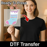 A smiling woman in a black shirt holds an InkMerge Quirky Vampire Christmas Stocking transfer. An arrow points from the sheet to her shirt. Text reads “Ready To Press” and “DTF transfers”—perfect for your ugly sweater party!.