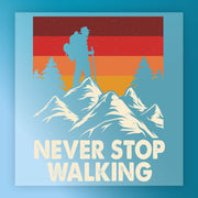 A hiker silhouette with a backpack stands on mountain peaks, surrounded by pines and a retro sunset. The InkMerge Retro Mountain Sunset Design DTF transfer features bold “NEVER STOP WALKING” text, perfect for heat press application.