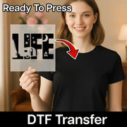 A smiling woman in a black shirt holds an InkMerge LIFE Camping Adventure Design DTF transfer sheet featuring nature icons. An arrow points from the sheet to her shirt. Text reads Ready To Press and DTF Transfer.