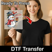 A woman in a black shirt holds InkMerge's A Cardinal Kind of Christmas Design—Ready To Press DTF transfer on premium film, showing a snowman with a top hat, scarf, cardinal, and present.