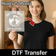 A smiling woman holding a sign with a soccer player and the text "SOCCER BOY BEST IN THE FIELD" printed on it.