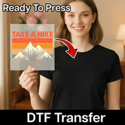 A smiling woman in a black shirt holds the "Minimalist Mountain Art - Heat Press Ready" sheet from InkMerge, featuring mountain art and TAKE A HIKE text—an easy custom apparel DTF transfer.