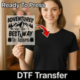 A woman in a black t-shirt holds the InkMerge “Adventures Are the Best Way to Learn” DTF transfer, featuring mountain and backpack graphics. A red arrow points to her shirt, showcasing the full-color, ready-to-press design.