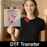 A woman in a black shirt holds the InkMerge "All Spruced Up Glittery Tree" DTF sheet, featuring a smiling pink cartoon Christmas tree with a star and “ALL SPRUCED UP” text above. A red arrow points to the shirt.
