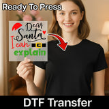 A woman in a black t-shirt holds an InkMerge "Dear Santa I Can Explain" DTF transfer sheet with festive graphics. Text above says Ready To Press, and below mentions it's perfect for holiday heat press projects.