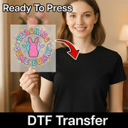 A woman holding a sign with a cartoon rabbit and the text "Teaching Some Bunny" on it, with a red arrow pointing to her chest.