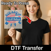 A smiling woman holding a sign with the text "LUD AND PROUD VOLLEYBALL WIFE" on it, with a red arrow pointing to the sign.
