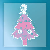 The InkMerge Gothic Christmas Tree with Skull Ornaments DTF transfer features a cartoon-style pink and purple tree with big eyes, a smiling mouth, skull ornaments, and a white skull topper on a blue gradient background.