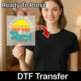A smiling woman in a black t-shirt holds an InkMerge Grand Canyon Retro Sunset Design Direct-to-Film transfer sheet. "Ready To Press" appears at the top, and "DTF Transfer" appears at the bottom.