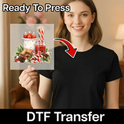 A smiling woman in a black shirt holds an InkMerge Festive Holiday Candles and Holly DTF transfer sheet with candles, candy canes, pinecones, and cinnamon sticks. Text reads “Ready To Press” and “DTF Transfer” with a red arrow.