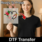 A smiling woman in a black shirt holds InkMerge’s Festive Holiday Elements—a clear sheet with colorful Christmas motifs. “Ready To Press” and “DTF Transfer” are displayed, showing it’s perfect for any heat press, highlighted by a red arrow.