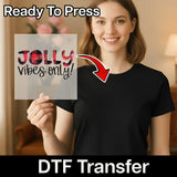 A smiling woman in a black shirt holds a transparent sheet that says "Jolly vibes only!" with a red arrow pointing to her shirt. Text above reads InkMerge Ready To Press, and below reads Jolly Vibes Only Christmas Design.