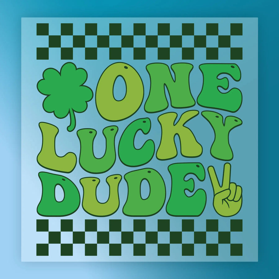 a collage of various images, including a cloverleaf, a peace sign, and a checkered pattern. The text "ONE LUCKY DUDDE" is prominently displayed in a stylized font, with the word "DUDE" being larger than the rest of the text.