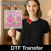 A woman holding a transparent sign with a cartoon apple and various school-related icons, smiling and posing for the camera.