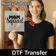 A smiling woman holding a sign with the text "MOM SQUAD" and a red arrow pointing to her chest.