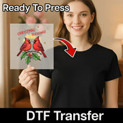 A smiling woman holds an InkMerge "Christmas Blessings Cardinals Design" DTF Transfer Sheet with two red cardinals, holly, and festive text. "Ready To Press" is at the top and "DTF Transfer" at the bottom—great for ugly sweater parties!.