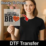 A smiling woman holding a sign with a basketball and heart design, with a red arrow pointing to the sign.