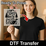A smiling woman in a black shirt holds a transparent Camp More Worky Less Design sheet by InkMerge—ideal for custom apparel. An arrow points to her shirt. Text reads Ready To Press and DTF transfers.