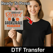 A woman holding a sign with the text "Stressed & Blessed & Basketball Obsessed" and a red arrow pointing to her chest.