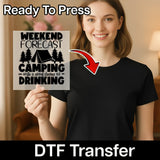 A woman in a black t-shirt holds InkMerge's "Weekend Forecast Camping with Drinking" DTF transfer featuring camping graphics, with "Ready To Press" above and "DTF Transfer" below.