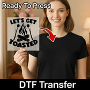 A smiling woman in a black shirt holds an InkMerge “LET'S GET TOASTED Campfire Fun” DTF Transfer featuring campfire marshmallows. An arrow points from the sheet to her shirt, with text: “Ready To Press” and “DTF Transfer.”.