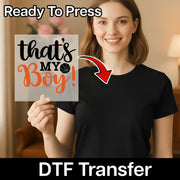 A smiling woman holding a sign with the text "That's my boy!" in front of her.