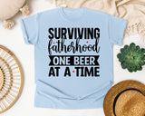 Surviving Fatherhood One Beer At A Time White graphic tee in Chambray