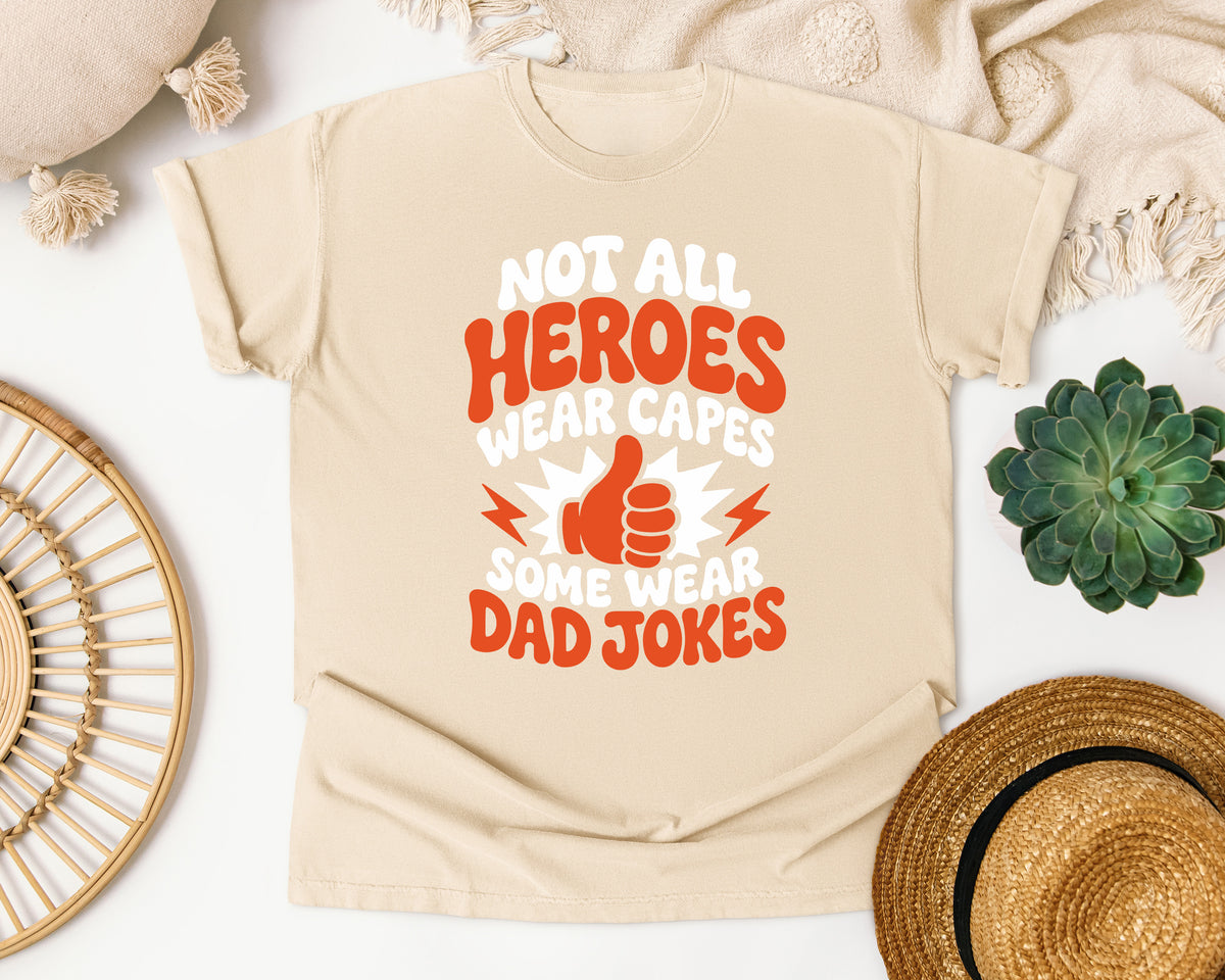 Not All Heroes Wear Capes Some Wear Dad Jokes Orange 2 graphic tee in Ivory