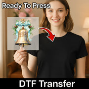 A smiling woman in a black shirt holds an InkMerge Vintage Christmas Bell with Holly transfer on premium DTF film. An arrow points from the transfer to her shirt. "Ready To Press" tops the image; "DTF Transfer" tails it—ideal for holiday heat pressing!.