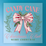 The Candy Cane Christmas Club Design by InkMerge features a pink and white striped bow with holly and berries on a blue background framed by green leaves. Text: "Candy Cane Christmas Club Merry Christmas". Great for holiday heat press or DTF film transfers.