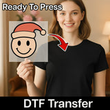 A woman in a black shirt holds a clear sheet with the Smiley Face Santa Hat Design by InkMerge. "Ready To Press" is at the top, "DTF transfer" at the bottom, and a red arrow highlights easy application with a heat press.