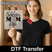 A smiling woman holding a sign with the text "Soccer Mom Life" on it, with a red arrow pointing to her chest.