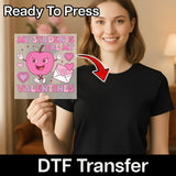A woman holding a Valentine's Day card with an apple character on it, smiling and posing for the camera.